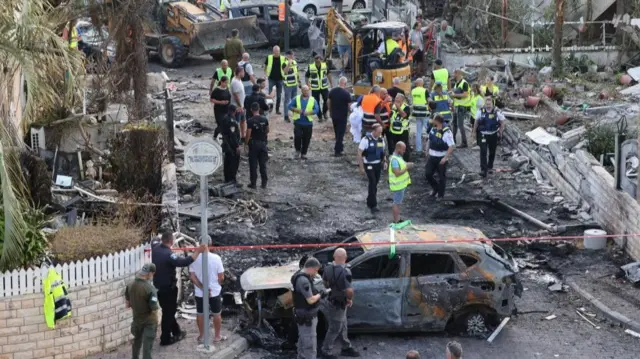 A damaged car and emergency workers in Israel