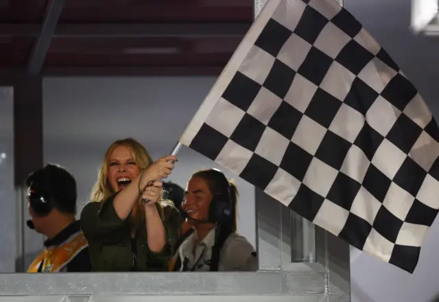 Kyle Minogue waves the chequered flag at the end of the Singapore Grand Prix