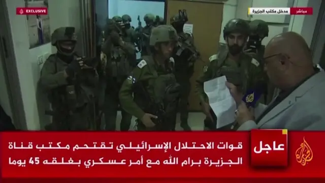 Multiple armed Israeli soldiers stand in a room