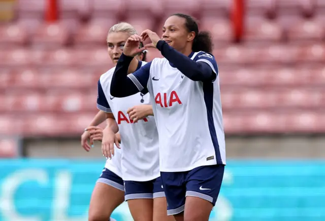 Spence celebrates her goal by making a heart sign with her hands