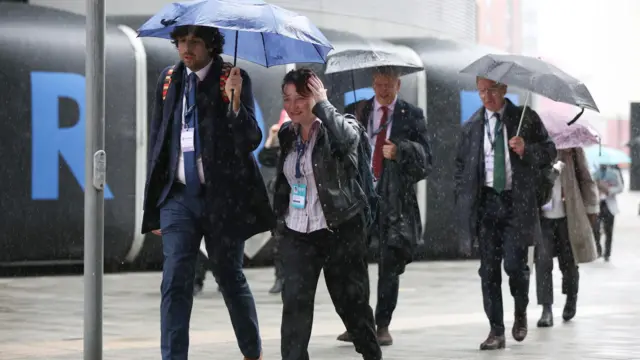 Labour party delegates make their way to the conference hall in Liverpool in a shower of rain