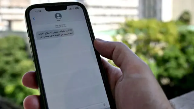 A person holds a phone with a message written in Arabic