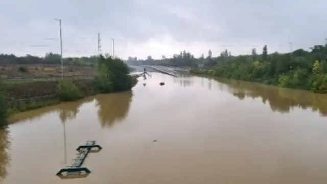 A road fully submerged by water - with just signs of a normal road towards the top of the photo