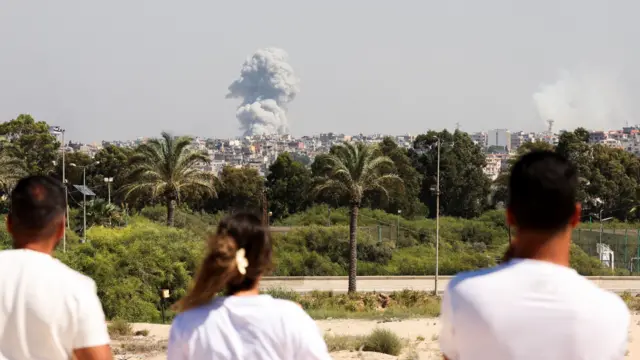 People watching plumes of smoke rising above buildings in Tyre, Lebanon