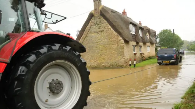 A tractor a vehicle stuck in flood water in Grendon, Northamptonshire. Photo: 23 September 2024