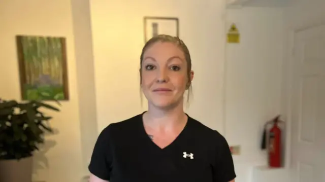 Viki Drury, a massage therapist and owner for Rejuvenated Therapy in Dunstable, is pictured in her premises. She is wearing a black top with her brown hair tied up.