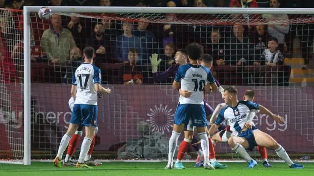 Morecambe's Jamie Stott heads an effort against the crossbar.