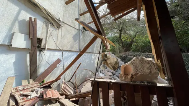 Damaged timber and rocket debris next to a house