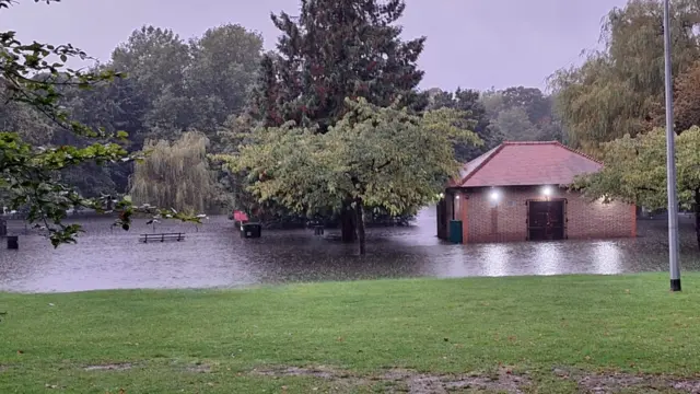 A bench and a pavillion can be seen in flood water