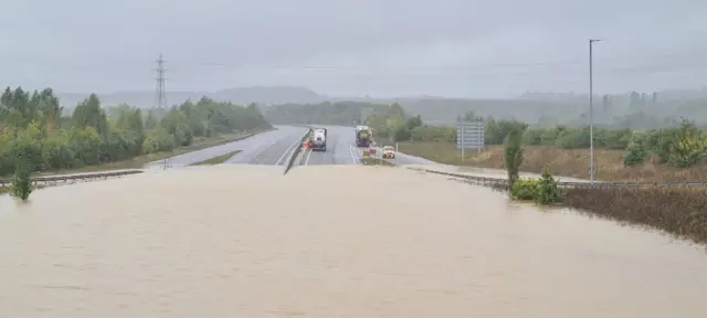 Tankers on the A421 behind where the flood water ends.