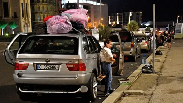 A line of parked cars loaded with luggage