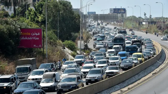 Vehicles queue across multiple lanes on a Lebanese highway as people flee north