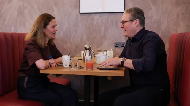 Keir Starmer and his wife in a booth with coffee mugs and a glass of juice