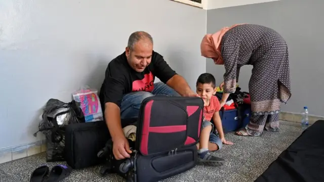 A family unpacks their belongings in a makeshift shelter at an educational centre in Beirut