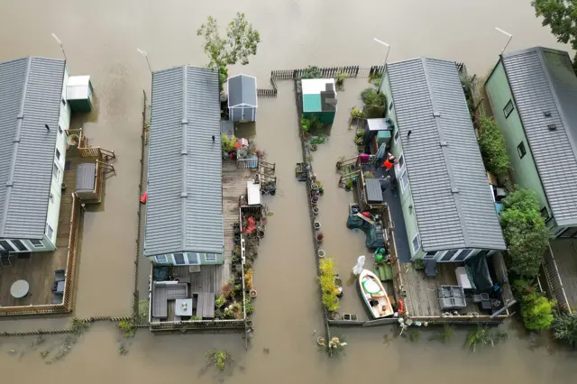 Cogenhoe Mill Holiday Park in Northamptonshire submerged by floodwater after the River Nene burst its banks. Four caravans are shown surrounded by flood water