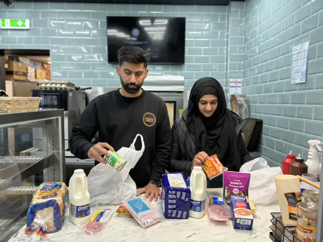 Asiyah and Jawad, Local Heroes creating food packages inside Day Today shop in Stenhousemuir