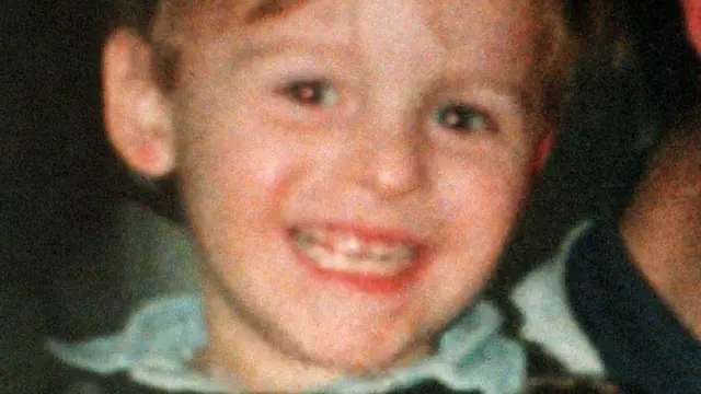 A grainy photo of a young boy, James Bulger, smiling at the camera