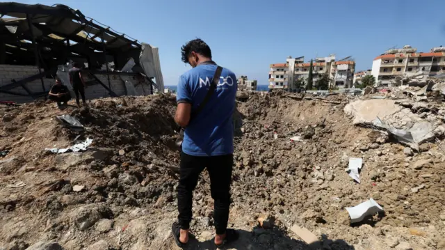 People inspect the damage at the site of an Israeli strike that hit the Lebanese seaside town of Jiyeh