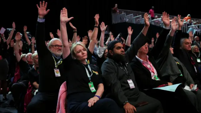 Delegate raise their hand as they vote in favour of a motion on the winter fuel payment