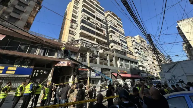 A crowd is gathered in front of the damaged building