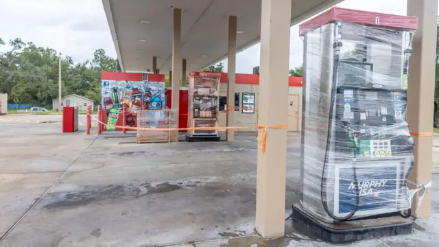 A gas station's pump is wrapped as the town prepares for Hurricane Helene in Perry, Florida