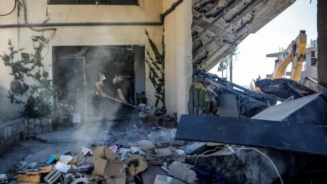 Man shovels debris after Israeli airstrike damages building in south Beirut