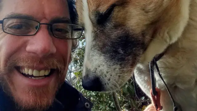 A man smiling beside a dog