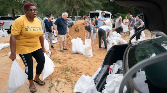 Tallahassee State professor Pamela Andrews carries sand bags to a car in preparation for possible flooding as Tropical Storm Helene heads toward the state's Gulf Coast