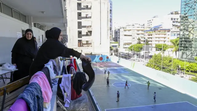 Lebanese women spreading laundry at a makeshift shelter in an educational institution hosting Lebanese people who fled from southern Lebanon