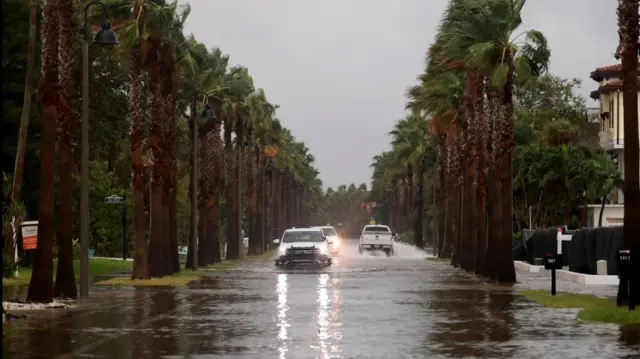 Cars drive on a flooded street