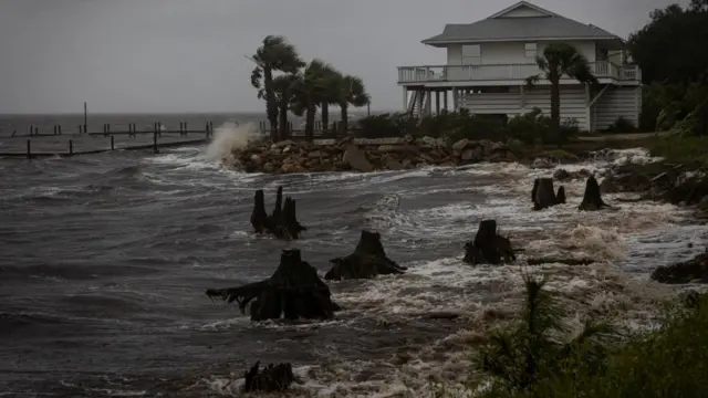 Waves batter a seawall in front of a house in Florida