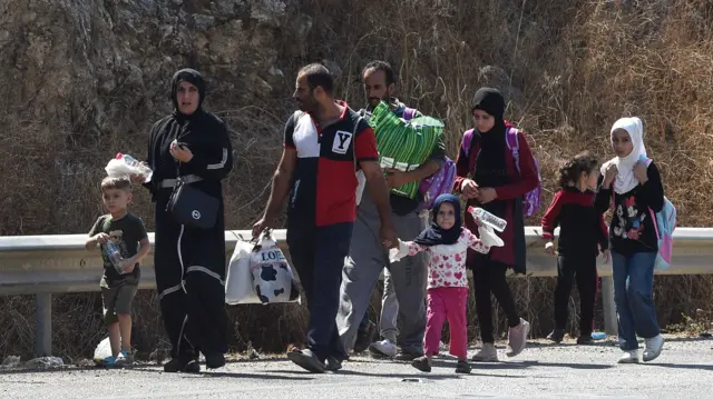 A family carries their belongings across a highway into Beirut