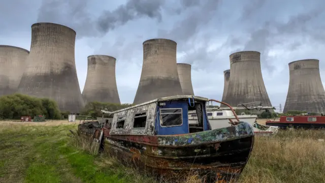 Narrow boats waiting for renovation stand in a marina yard next to the eight cooling towers at the station