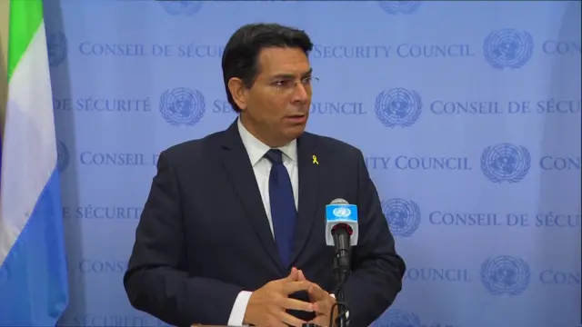 Danny Danon wearing a suit standing at a microphone