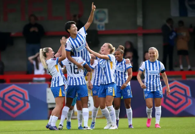 Brighton players lift Seike aloft as they celebrate her hat-trick goal together