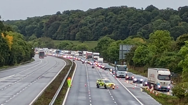 Police block off the highway with traffic cones, which direct an enormous queue of motorists to an offramp