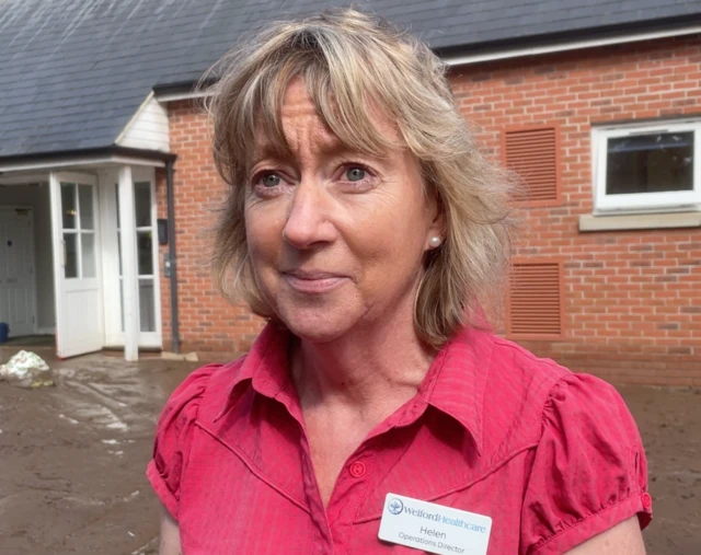 Helen Bayliss has blonde hair and is wearing a pink top