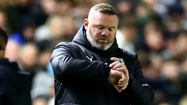 Plymouth manager Wayne Rooney looks at his watch