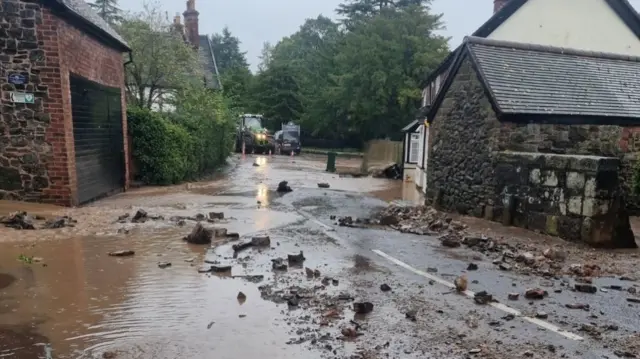 A rock strewn road with water flowing down it