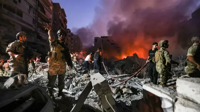 Lebanese army soldiers gather over the rubble of a levelled buildings as people flight the flames, following Israeli air strikes in the Haret Hreik neighbourhood of Beirut's southern suburbs