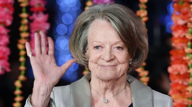 Dame Maggie Smith waving to a camera