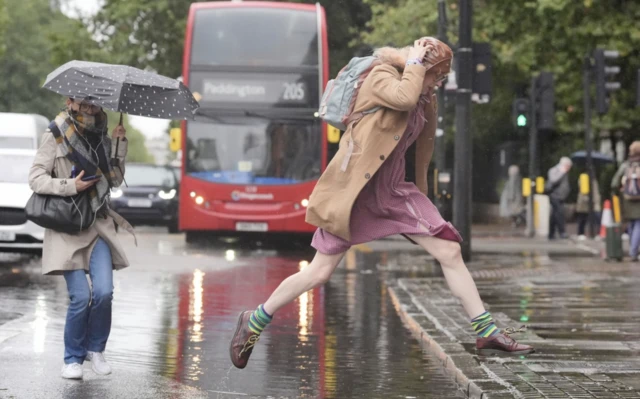 A person jumps over a puddle on Euston Road in London after parts of England were lashed by heavy rain and flooding in the early hours of Frida