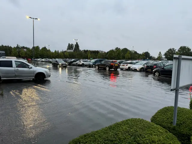 Cars parked in a car park which is flooded with water