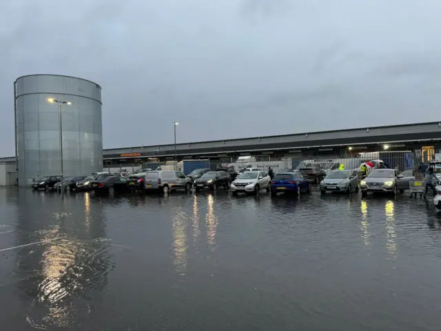 A row of cars parked in a car park flooded with water