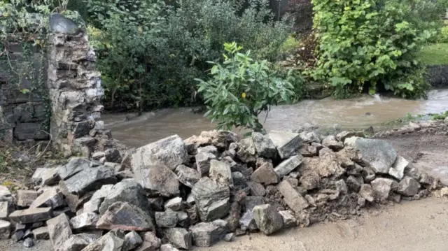 A collapsed wall in All Stretton with water surrounding it