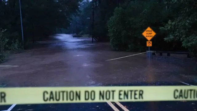 Warning tape tells drivers not to enter a section of road in Atlanta, Georgia which has been submerged by Storm Helene