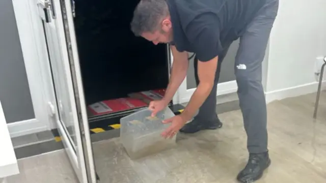 A man trying to pick up water in a plastic box