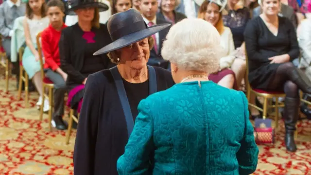 Maggie Smith standing in front of the queen at her investiture ceremony at Windsor Palace