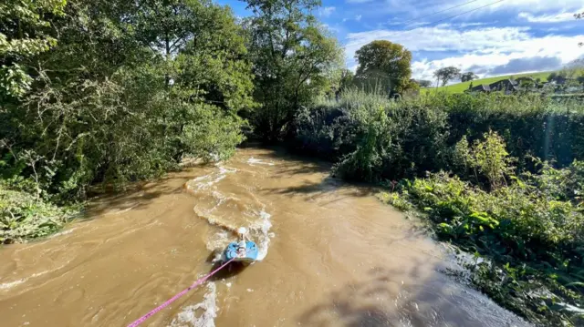 A monitor on the end of a piece of cord, measuring water flow in a small river