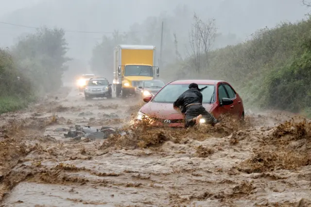 A local resident helps free a car that became stranded in a stretch of flooding road as Tropical Storm Helene strikes, on the outskirts of Boone, North Carolina